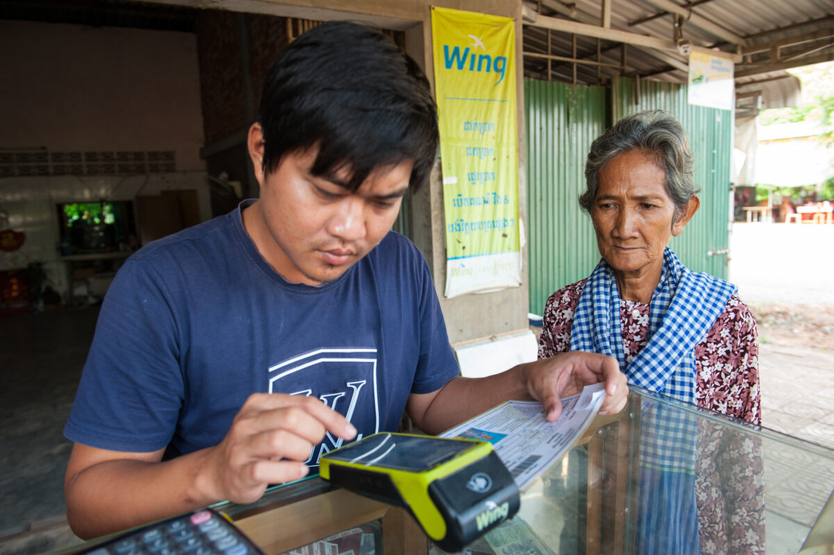 A payment agent processes a cash transfer in Kep Province
